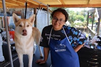 a woman standing next to a husky dog